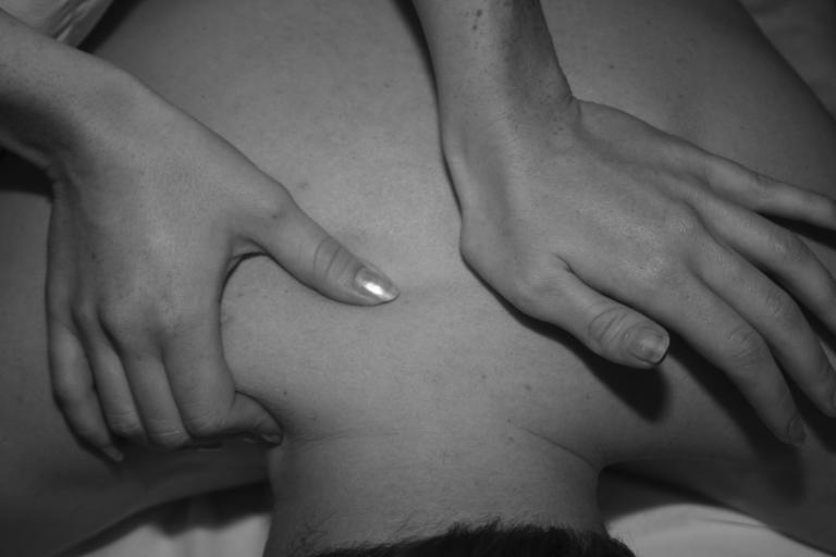 Masáž chrbta, ženské ruky, čiernobiele.jpg